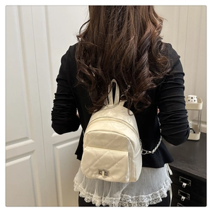 Close-up of quilted cream mini backpack featuring chain straps and metal twist lock detail