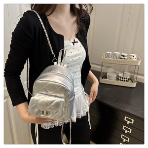 Close-up of silver quilted mini backpack with chain strap and metallic clasp detail