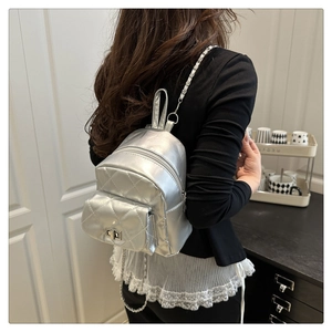 Detail of silver metallic quilted mini backpack with chain strap on a fashion model