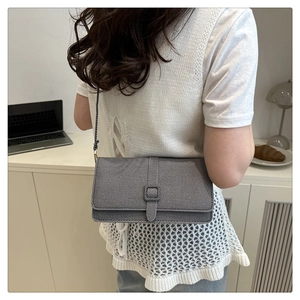Détail du sac à bandoulière en denim gris avec boucle carrée et fine sangle tressée