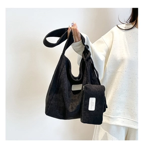 Detailed close-up of black corduroy tote bag texture and white fabric logo label