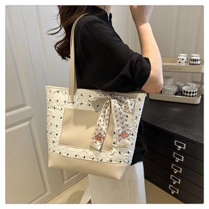 Detail of quilted tote bag with decorative scarf and PU leather trim in a home setting