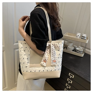 Detail of cream tote bag with black bow embroidery and decorative silk scarf detail