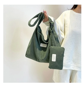 Close-up of green corduroy tote bag texture and matching small pouch held by a model