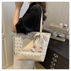 Detail of cream quilted tote bag with black bow print and decorative floral scarf strap