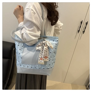 Detail of light blue quilted tote bag featuring butterfly embroidery and scarf handle