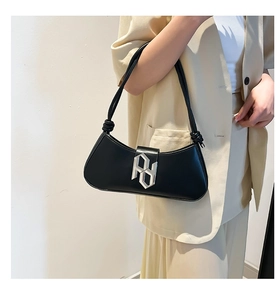 Detail of minimalist black PU shoulder bag with silver logo and decorative knot strap