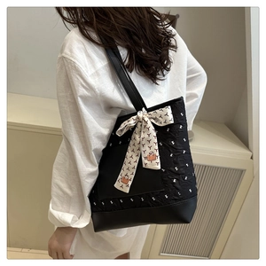 Detail of black quilted tote bag with white geometric print and decorative silk scarf