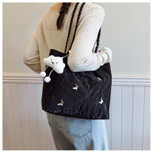 Close-up of black pleated tote bag with silver butterfly charms and fluffy cloud charm
