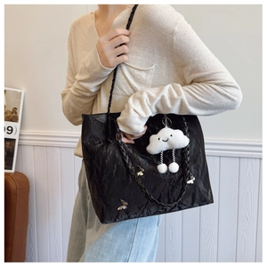 Detail of black tote bag with crinkled texture, butterfly charm and cloud keychain