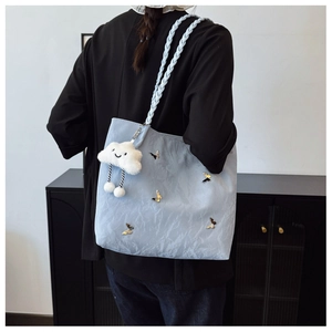 Detail of light blue tote with metal butterfly accents and braided handle strap