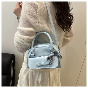 Side view of light blue bow handbag with checkered ribbon on a model for scale