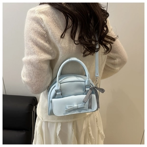 Close-up of light blue mini Boston bag with bow pocket and plaid ribbon handle detail