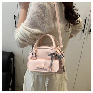 Detail of pink leather handbag with bow ribbon and crossbody strap on model
