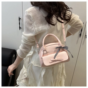 Detail of light pink bow handbag with checkered ribbon handle and cross-body strap