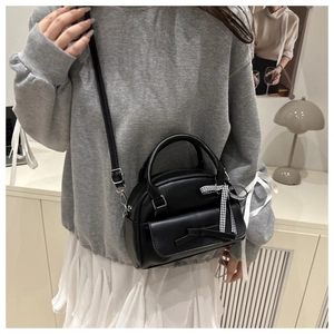 Detail of black bow-knot Boston bag with textured PU leather and dual-style ribbon decor