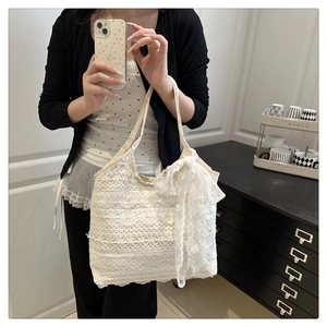 Macro detail of layered lace floral texture and oversized bow on cream tote bag