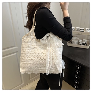 Detail of white lace tote bag featuring elegant lace layers and a large side bow decoration