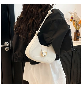 Detail of white semi-circle saddle bag featuring a large gold D-ring and knotted strap