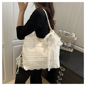 Close-up of white lace woven tote bag featuring a large decorative lace bow detail