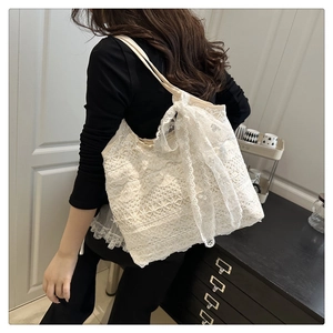 Detailed view of white floral lace tote bag with large decorative bow on model