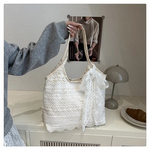 Detailed close-up of ivory lace tote bag with floral crochet pattern and side bow