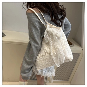 Detailed close-up of a white lace tote bag with a large bow detail for beach vacations