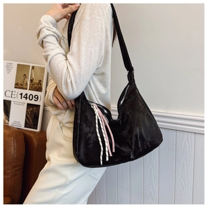 Detail of black crescent hobo bag with woven cord charm on casual shoulder strap