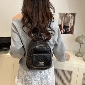 Chic quilted black leather bucket backpack with chain straps shown on a model
