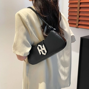 Minimalist black leather underarm bag with a silver geometric buckle and knotted shoulder strap