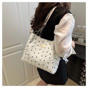 Dettaglio borsa shopper bianca con motivi a fiocco nero e tracolla a catena elegante