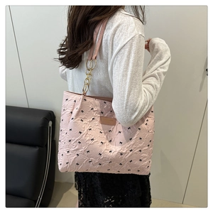 Détails au dos d'un sac cabas matelassé rose avec imprimé nœuds et chaîne dorée