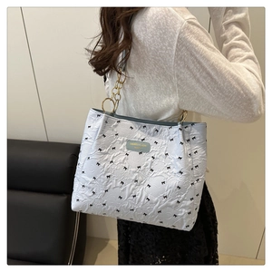 Dettaglio borsa tote azzurra plissettata con fiocchi neri e catena in metallo dorato