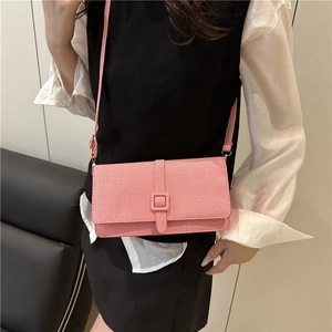 Sac à bandoulière carré rose texturé avec boucle dorée porté à l'épaule pour l'été