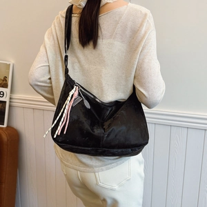 Borsa hobo nera capiente in pelle minimalista con ciondolo unico per l'estate 2025