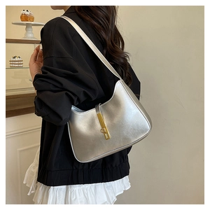 Silver metallic leather hobo bag with gold metal clasp shown on a model's shoulder
