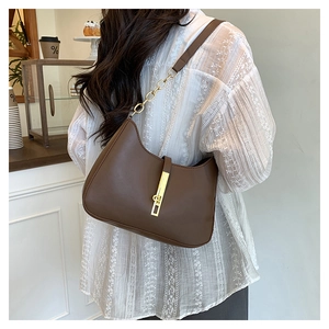 Dettaglio della borsa hobo in pelle marrone scuro con finiture dorate sulla modella