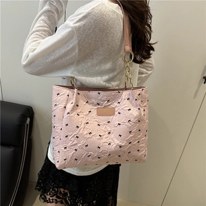 Borsa tote trapuntata rosa con fiocchi neri e catene dorate portata a spalla