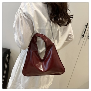 Dettaglio macro della borsa hobo asimmetrica bordeaux lucido con catena d'argento