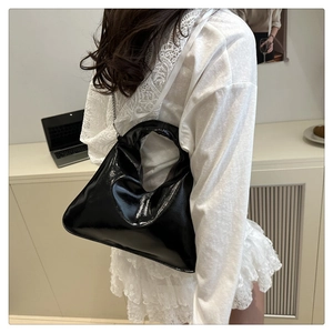 Detail of glossy black shoulder bag with silver chain and unique circular hollow handle