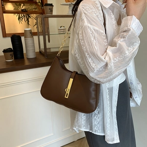 Deep brown leather underarm bag with gold chain strap shown in a cafe setting