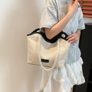 Close-up of hand-woven straw tote bag with black trim and thick cotton rope shoulder straps