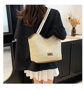 Detail of large straw beach tote with cotton rope handle and leather fashion brand tag