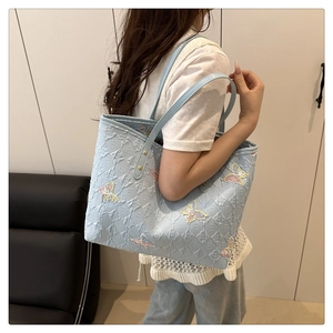 Detail of light blue tote bag featuring elegant butterfly embroidery and diamond quilting