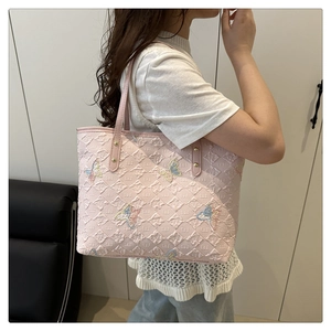Detailed view of pink tote bag with embossed texture and colorful butterfly embroidery