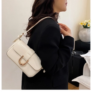 Model view of chic cream glossy shoulder bag with iconic gold U-buckle detail