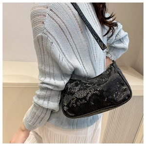 Close-up of black snake pattern texture on shoulder bag with silver metallic hardware details