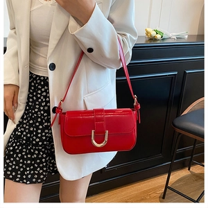 Detailed view of the glossy burgundy leather shoulder bag with gold horseshoe buckle