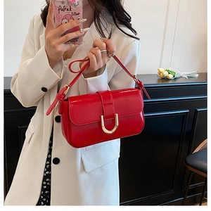 Detail of glossy wine red patent leather shoulder bag with golden U-shaped buckle