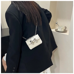 Detailed back view of white mini crossbody bag with silver bow and chain strap
